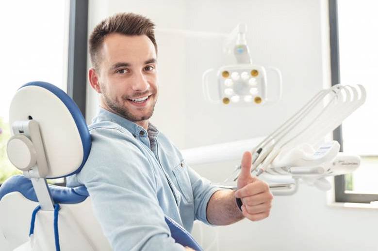 man in dental chair giving thumbs up