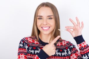 a patient smiling and holding their Invisalign aligner in North York