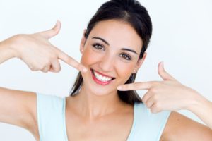 young woman pointing to her bright smile